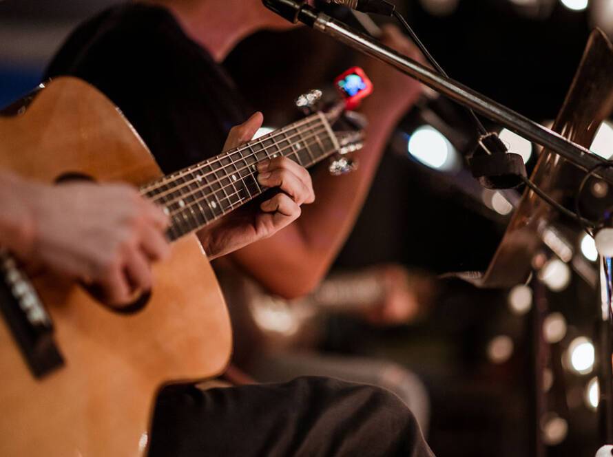 Close-up of a musician playing an acoustic guitar during a live performance at The Pavilion in Marion, Illinois