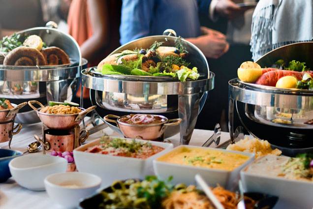 Buffet table with assorted dishes and chafing dishes filled with fresh food at a catered event