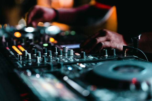 Close-up of a DJ mixing music on a soundboard with colorful lights and controls