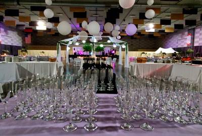 Champagne glasses arranged on a table for a formal event in The Pavilion Expo Hall, with elegant lighting and décor in the background.