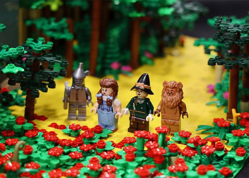 Close-up of a LEGO Wizard of Oz display featuring Dorothy, the Tin Man, Scarecrow, and Cowardly Lion in a colorful forest scene.