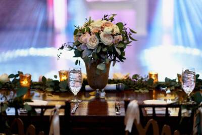 Elegant wedding table setup with floral centerpiece, candles, and glassware on a wooden table.