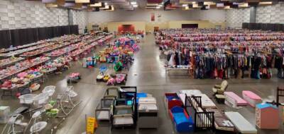 The Pavilion Expo Hall hosting a large community sale event with rows of tables and racks filled with clothes, toys, and furniture.