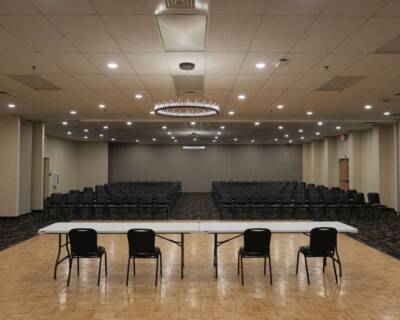 The Pavilion Ballroom set up for a conference with rows of chairs, long tables at the front, and modern ceiling lighting.