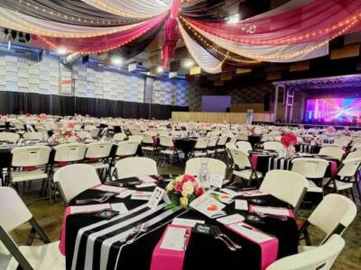 The Pavilion Expo Hall decorated for a banquet event with black, white, and pink table settings under draped ceiling lights.