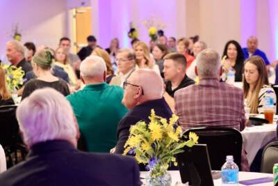 Guests seated at decorated tables during an event at The Pavilion, with floral centerpieces and purple ambient lighting.
