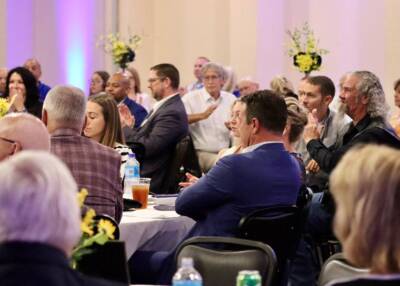 Guests seated at round tables enjoying an event at The Pavilion, with floral centerpieces and soft ambient lighting.