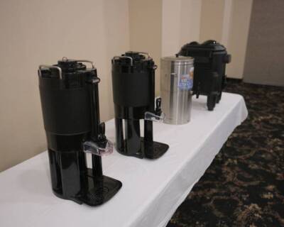 Coffee and beverage service setup at The Pavilion with dispensers for coffee and iced tea on a covered table